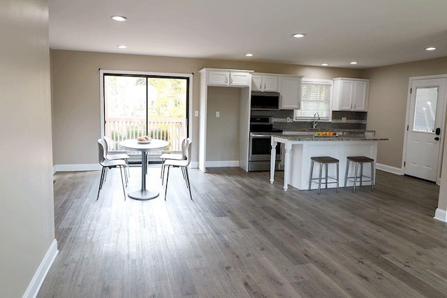 kitchen featuring dark stone counters, stainless steel appliances, a center island, white cabinetry, and a breakfast bar area