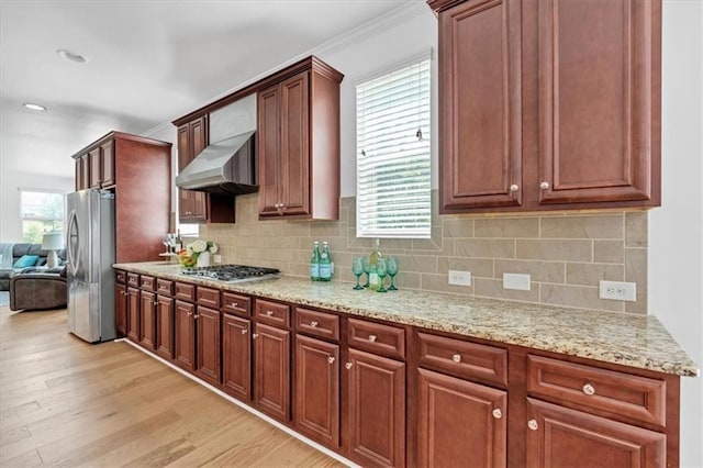 kitchen featuring extractor fan, light wood-style flooring, stainless steel appliances, backsplash, and light stone countertops