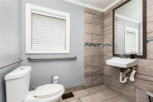 half bath featuring toilet, a sink, visible vents, and crown molding