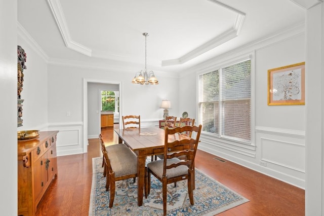 dining room with a raised ceiling, crown molding, a chandelier, and hardwood / wood-style flooring