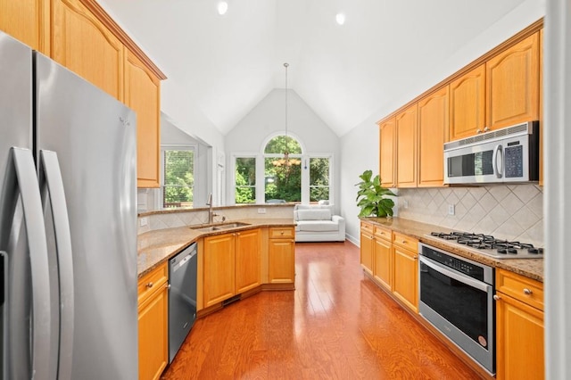 kitchen featuring sink, light stone counters, pendant lighting, decorative backsplash, and appliances with stainless steel finishes