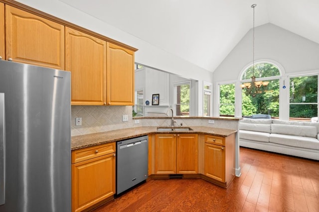 kitchen featuring light stone countertops, sink, an inviting chandelier, tasteful backsplash, and appliances with stainless steel finishes