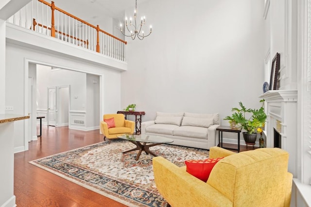 living room featuring a towering ceiling, dark hardwood / wood-style floors, and an inviting chandelier