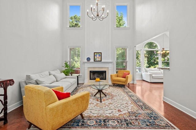 living room with dark wood-type flooring, a high ceiling, and an inviting chandelier