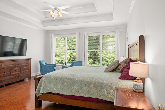 bedroom featuring ceiling fan, a raised ceiling, wood-type flooring, and ornamental molding