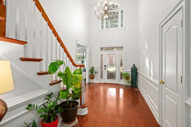 entryway with a towering ceiling, an inviting chandelier, and dark wood-type flooring