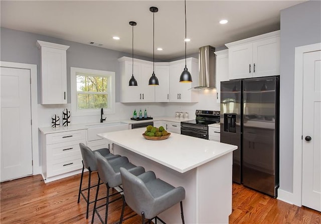 kitchen with wall chimney exhaust hood, stainless steel appliances, sink, and white cabinets