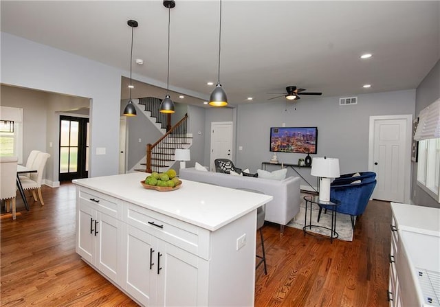 kitchen featuring pendant lighting, white cabinets, a kitchen bar, hardwood / wood-style flooring, and a center island