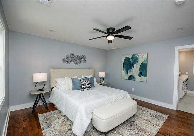 bedroom with dark wood-type flooring, ceiling fan, and ensuite bath