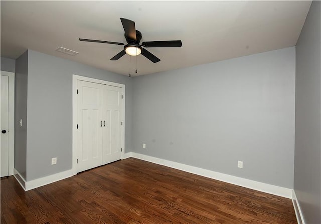 unfurnished bedroom with ceiling fan, dark hardwood / wood-style flooring, and a closet