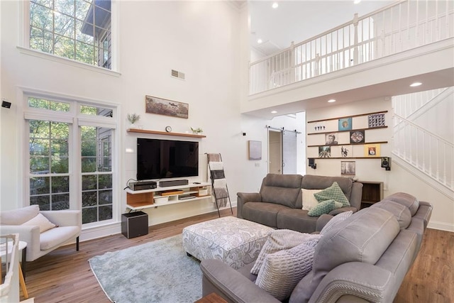 living area with recessed lighting, visible vents, a barn door, wood finished floors, and stairs