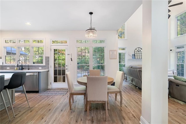 dining space with recessed lighting, a notable chandelier, light wood-style flooring, and a towering ceiling