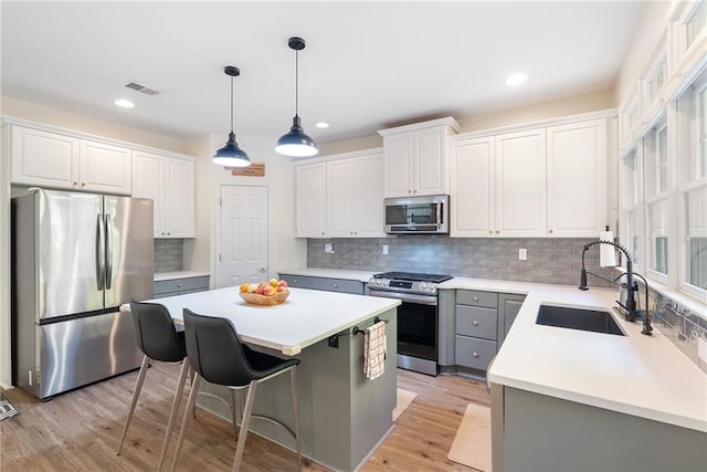 kitchen with a center island, light wood finished floors, visible vents, appliances with stainless steel finishes, and a sink