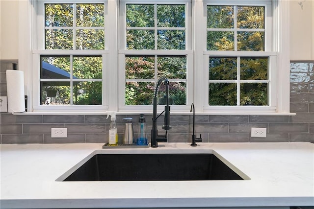 interior space featuring tasteful backsplash, light countertops, a sink, and white cabinetry