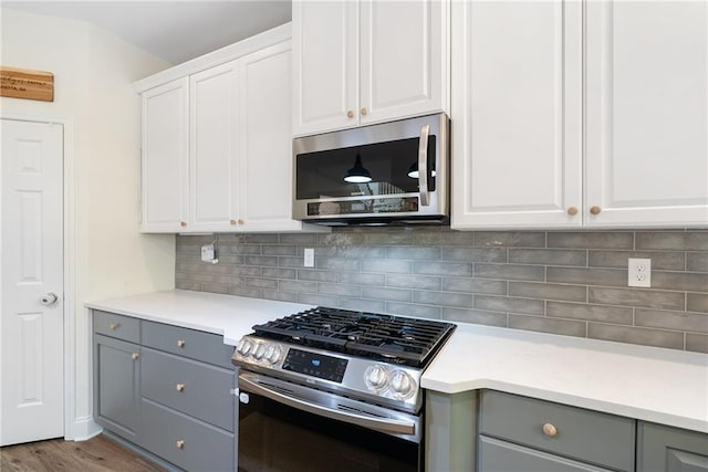 kitchen featuring stainless steel appliances, tasteful backsplash, gray cabinets, light countertops, and white cabinetry