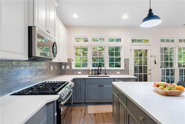 kitchen with tasteful backsplash, gray cabinets, stainless steel appliances, light countertops, and a sink