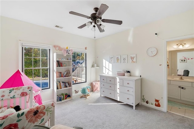 bedroom featuring baseboards, visible vents, light colored carpet, ensuite bath, and a sink