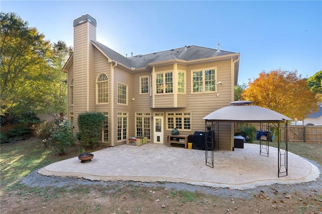 back of property featuring a patio area, fence, a chimney, and a gazebo