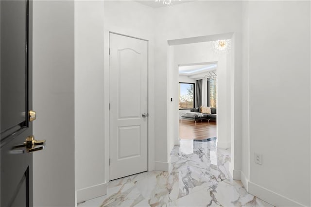 corridor featuring marble finish floor and baseboards