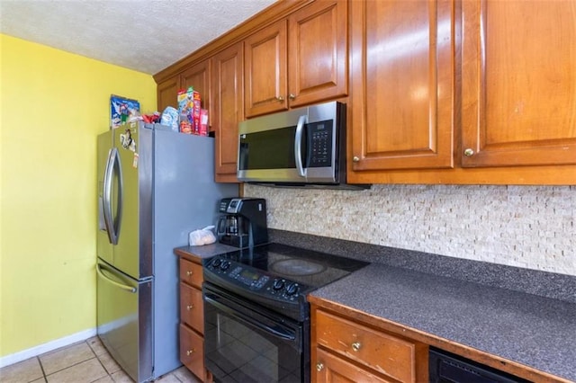 60 Boardwalk Ave, Covington, GA 30016 - kitchen with appliances with stainless steel finishes, dark countertops, decorative backsplash, light tile patterned floors, and brown cabinetry