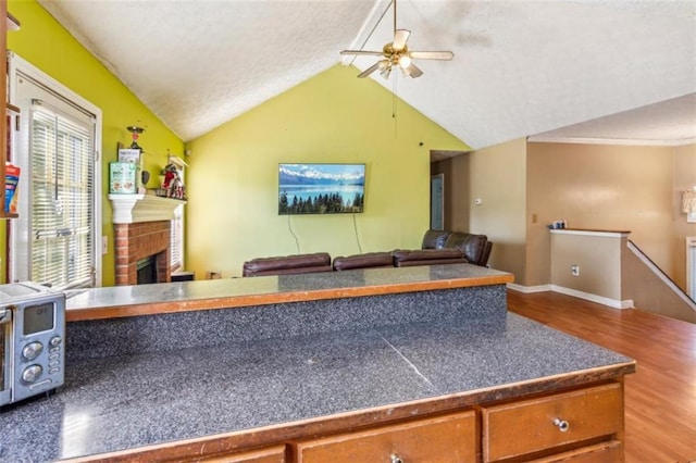 60 Boardwalk Ave, Covington, GA 30016 - kitchen featuring a ceiling fan, open floor plan, wood finished floors, vaulted ceiling, and a fireplace