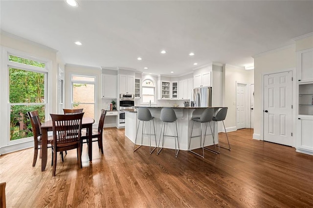 3714 Westbrooke Cir NE, Brookhaven, GA 30319 - kitchen with stainless steel appliances, crown molding, a breakfast bar, white cabinets, and glass insert cabinets