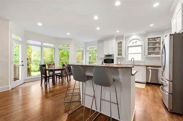 3714 Westbrooke Cir NE, Brookhaven, GA 30319 - kitchen featuring appliances with stainless steel finishes, ornamental molding, a kitchen breakfast bar, dark stone counters, and a kitchen island