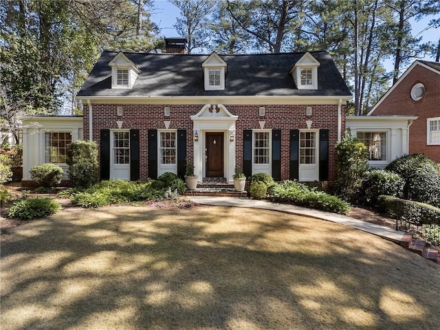 view of front of home featuring brick siding and a chimney