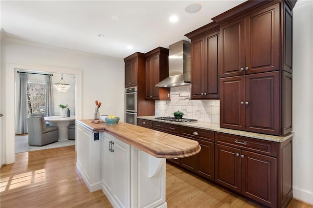 kitchen with stainless steel appliances, wall chimney range hood, backsplash, and light wood-style floors