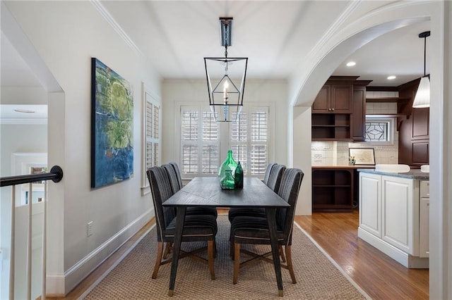 dining space with a chandelier, recessed lighting, baseboards, light wood-style floors, and crown molding