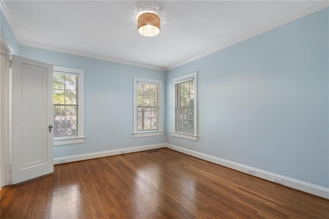 empty room with a healthy amount of sunlight, wood-type flooring, and baseboards