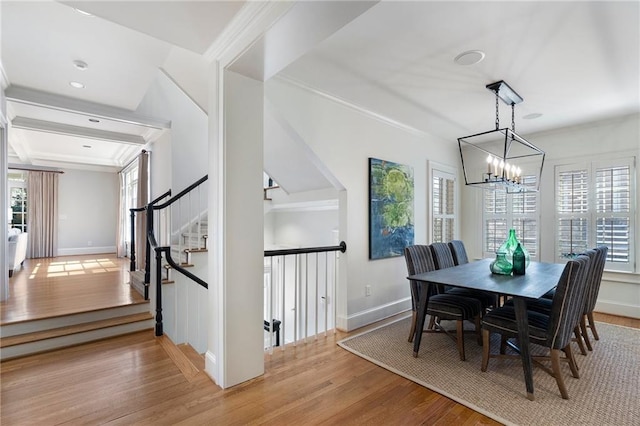 dining room with baseboards, a chandelier, light wood-style flooring, and crown molding