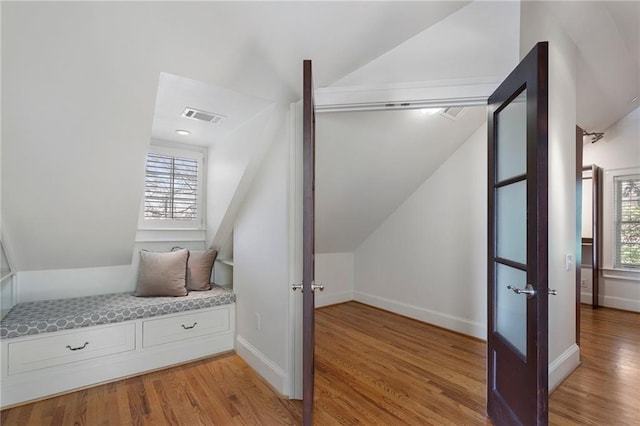 interior space featuring light wood finished floors, visible vents, vaulted ceiling, and a wealth of natural light