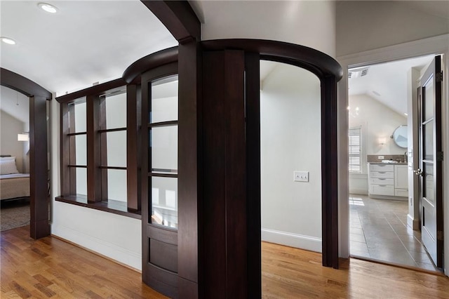 interior space with arched walkways, visible vents, lofted ceiling, and wood finished floors