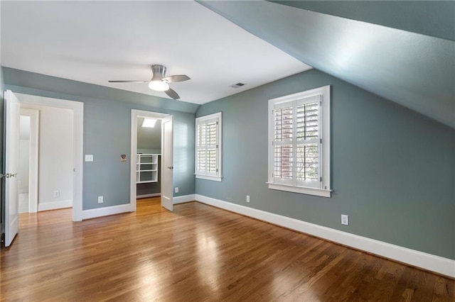 unfurnished bedroom with visible vents, a spacious closet, baseboards, and wood finished floors