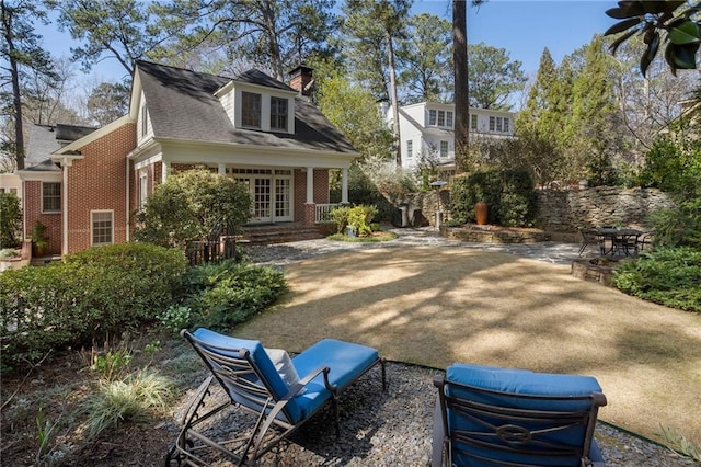 exterior space featuring brick siding, a patio area, a chimney, and french doors