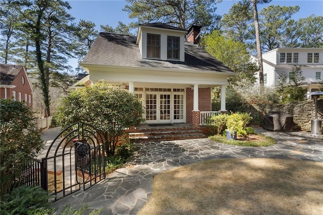 view of front of property featuring french doors, fence, and brick siding