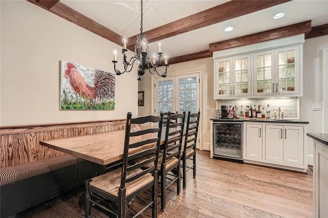 dining area featuring an inviting chandelier, beamed ceiling, light hardwood / wood-style floors, wine cooler, and bar