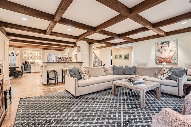 living room featuring beamed ceiling, an inviting chandelier, light wood-type flooring, and coffered ceiling