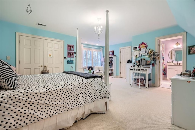 carpeted bedroom featuring an inviting chandelier, a closet, and ensuite bath