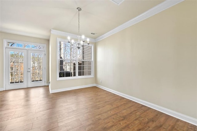 unfurnished dining area with wood finished floors, baseboards, french doors, an inviting chandelier, and crown molding