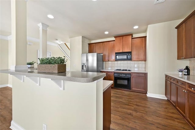 kitchen featuring black appliances, a breakfast bar area, light countertops, and brown cabinetry