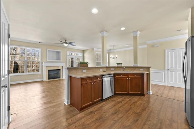 kitchen featuring brown cabinets, stainless steel appliances, light countertops, open floor plan, and a sink