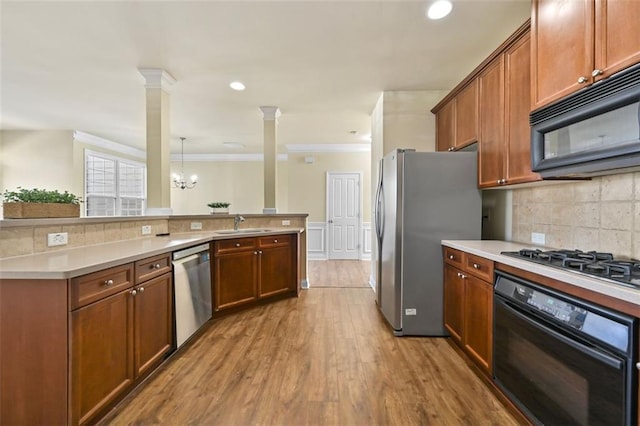 kitchen with brown cabinets, light countertops, hanging light fixtures, a sink, and black appliances