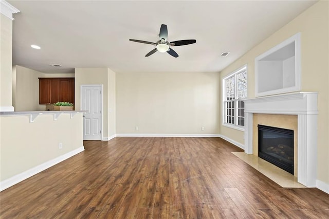 unfurnished living room with ceiling fan, a fireplace, baseboards, and dark wood-style flooring