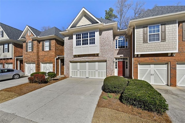 multi unit property featuring a garage, brick siding, and driveway