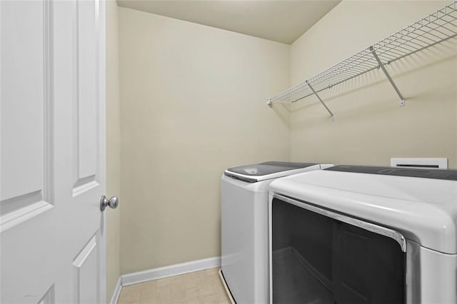 laundry room featuring laundry area, washing machine and dryer, baseboards, and light floors