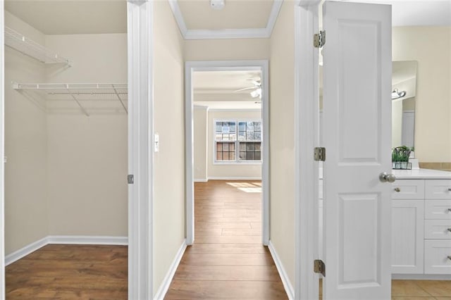 hallway with light wood-style floors, baseboards, and crown molding