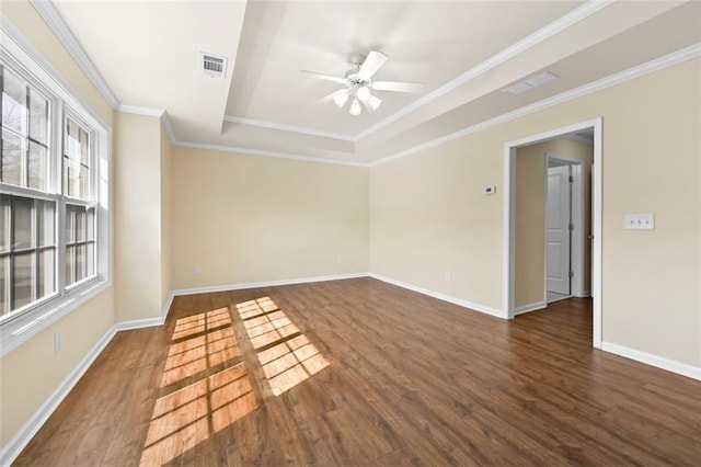 spare room with dark wood-style floors, a raised ceiling, visible vents, and ornamental molding