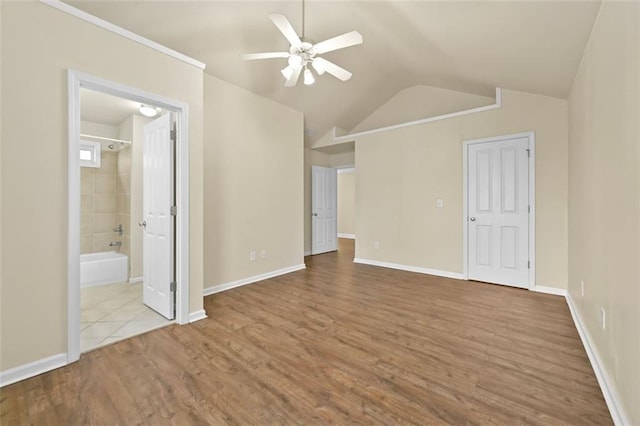 unfurnished bedroom featuring light wood finished floors, lofted ceiling, a ceiling fan, connected bathroom, and baseboards